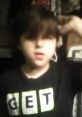 Child with trendy hairstyle wearing a black "GET" t-shirt, embodying a fun and quirky spirit aligned with pizza fandom.
