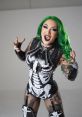 Shotzi Blackheart poses in a striking skeleton bodysuit, showcasing her edgy style and vibrant green hair.