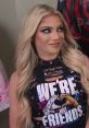 Alexa Bliss sporting a stylish black top with the phrase "We're Not Friends," showcasing her signature glam look.