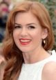 Isla Fisher smiling gracefully with long red hair, wearing a white dress and striking red lipstick at a public event.
