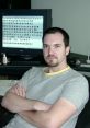 Duncan McKissick seated at a desk with a computer screen displaying game assets, involved in Age of Empires development.