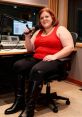 Heather Raina in a recording studio wearing red, sitting with a microphone, showcasing her passion for broadcasting.