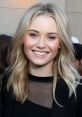 Virginia Gardner smiles brightly at a social event, showcasing her blonde hair and stylish outfit in a casual setting.