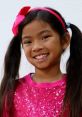 Smiling girl wearing a pink sequined shirt and matching headband, embodying fun and joy from "Emma (Toys And Colors) 2020".