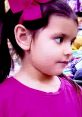 Child with a pink bow, wearing a bright pink shirt, enjoying colorful toys in a playful shopping environment.