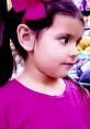 Young girl with pigtails and a pink bow, wearing a magenta shirt, looking curiously in a colorful market setting.