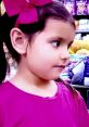 Young girl with a pink bow and shirt, looking curiously while shopping, embodying innocence and wonder in 2021.