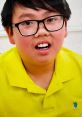 Child with glasses wearing a bright yellow polo shirt, smiling, showcasing Vinnie Toy and Colors from 2007-2020.