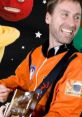 Smiling musician in an orange space suit playing guitar, with colorful planets in the background, showcasing 'Mooseclumps' theme.