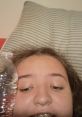 Close-up selfie of Marissa Allen resting with a water bottle beside her, cozy on a striped pillow background.