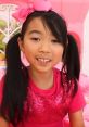 Lucy smiles brightly in a pink outfit featuring sequins, embodying the cheerful spirit of "Toys And Colors" Season 1.