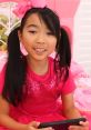 Young girl in a sparkly pink dress and bow, engaged with a toy tablet in a colorful room, promoting creativity and fun.