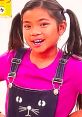 Young girl in a pink shirt and cute cat overalls smiles brightly, inspired by Emma Toys And Colors creativity.