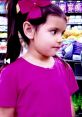 Young girl in a pink shirt with a large bow, browsing in a colorful toy aisle, inspired by Ellie Toys and Colors 2011.