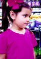 Young girl in a pink shirt and bow, exploring vibrant colors in a store, inspired by Toys And Colors Ellie 2011.