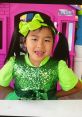 Happy Jannie character in a sparkling green outfit with playful pigtails and a big bow, ready for colorful adventures!