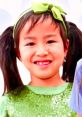 Smiling girl wearing a green outfit with a bow, embodying the playful spirit of Toys and Colors with cheerful energy.