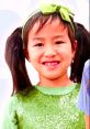 Smiling girl in a green sparkly top and bow, showcasing joy in vibrant colors, perfect for Toys and Colors Jannie fans.