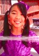 Smiling girl in a sparkling purple dress with pigtails and a bow, showcasing vibrant colors from Lucy Toys & Colors.
