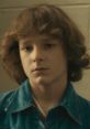 Young boy with curly hair wearing a denim jacket, gazing thoughtfully, evoking nostalgia and innocence.