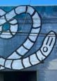 Colorful street art featuring a whimsical, cartoonish worm design on a blue wall. Perfect representation of Wormboy style.