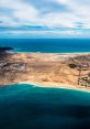 Aerial view of Eiland's coastal landscape featuring sandy beaches and vibrant turquoise waters under a partly cloudy sky.
