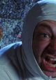 A man in a white hooded outfit yells dramatically, capturing a moment of intense comedic expression reminiscent of absurd humor.
