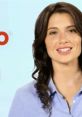 Smiling woman in a blue shirt promoting Priceline in a bright, engaging advertisement setting.