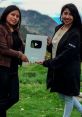 Two women proudly holding a YouTube Play Button award outdoors, celebrating their achievement in content creation.