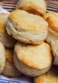 Fluffy, golden-brown biscuits stacked in a basket, perfect for breakfast or a comforting snack. Savory goodness awaits!