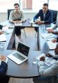 Professionals engaged in a meeting around a table with laptops, documents, and coffee, discussing important business strategies.