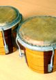 Two wooden bongos with metallic rims, showcasing their polished surface and vibrant tones, set on a wooden floor.