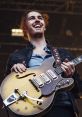 Hozier performs passionately with a vintage guitar, showcasing his unique style and musical talent at a live concert.
