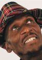 Jimmy Cliff smiling while wearing a colorful plaid hat, showcasing his vibrant personality and iconic reggae style.