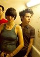 Stylish group with unique haircuts in a dimly lit hallway, capturing the essence of alternative music culture.