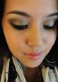 Close-up of a woman with elegant green eyeshadow, natural lips, and a stylish scarf, showcasing a chic makeup look.