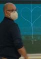 Chad Saïm teaching in a classroom, drawing a heart on a chalkboard while wearing a mask. Engaging educational setting.