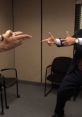Two men in an office playfully pointing finger guns at each other, showcasing a humorous moment in a professional setting.