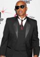 Stylish man in a tuxedo with sunglasses at an awards event, exuding confidence and charisma.