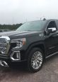 GMC Sierra Denali in black with chrome accents, showcasing a powerful design and luxury features on a gravel surface.