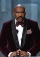 Steve delivers a speech in a formal burgundy suit with a bow tie, emphasizing an important moment on stage.