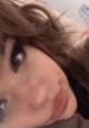 Close-up of a young woman with brown hair and expressive eyes, showcasing a playful and engaging personality.