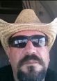 Leroy Sinclair wearing sunglasses and a straw cowboy hat, showcasing a confident expression against a vehicle backdrop.
