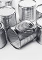 Collection of metallic tin cans arranged on a white surface, showcasing their classic round shape and textured design.