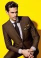 Stylish man in a tailored brown suit with striped shirt and pocket square against a vibrant yellow background.