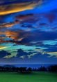 Dramatic sunset paints the sky with vibrant colors over a serene landscape, blending blues and oranges beautifully.