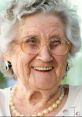 Cheerful elderly woman with gray hair, glasses, and pearls, embodying the warmth and love of a beloved granny.