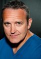 Mark Moraghan, narrator of Thomas & Friends Series 17-21, close-up portrait with confident expression in blue shirt.