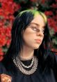 Billie Eilish with striking green and black hair, wearing stylish shades and layered necklaces against a floral backdrop.