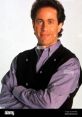 Jerry Seinfeld poses confidently, wearing a dark vest over a light shirt, showcasing his signature style and charm.
